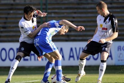 Javi Navarro pugna por el balón entre dos defensas.