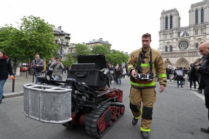 Un bombero, junto con el robot que ayudó a los bomberos en el incendio de Notre Dame, este martes.