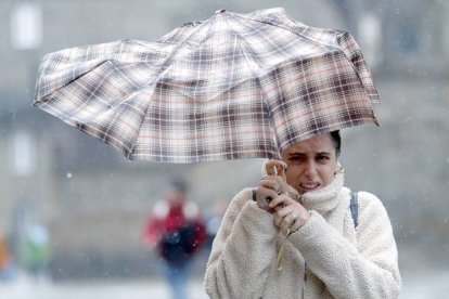 Una mujre se protege de la lluvia y el viento con un paraguas. LAVANDEIRA JR