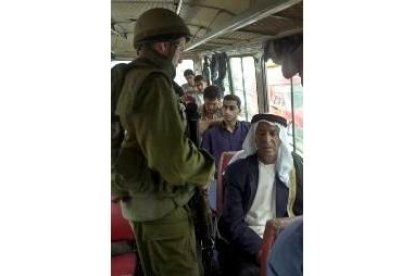 Un soldado registra a varios palestinos en un autobús, en Hebrón