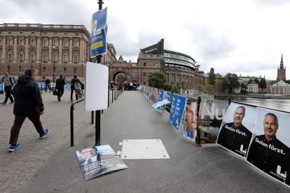 Varias personas caminan junto a carteles electorales en el Parlamento sueco. FRANZEN