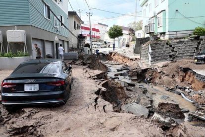 Un vehiculo permanece atrapado entre el lodo en una calle destruida tras el fuerte terremoto.