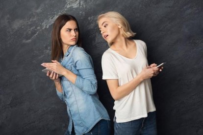 Una chica espía el móvil de su amiga.