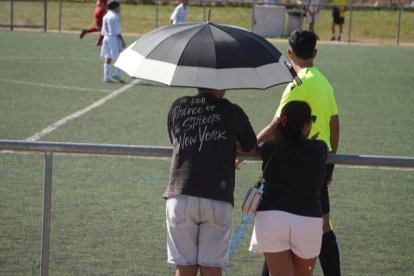 Dos aficionados disfrutan del fútbol este sábado en León protegidos del calor por una paragüas. J. NOTARIO