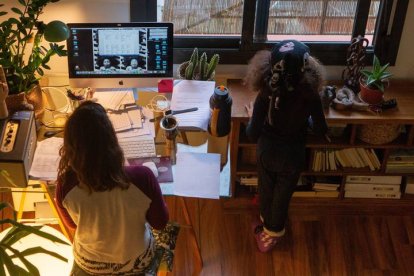 Una mujer realiza teletrabajo en su casa mientras su hija juega a su lado. ENRIC FONTCUBERTA