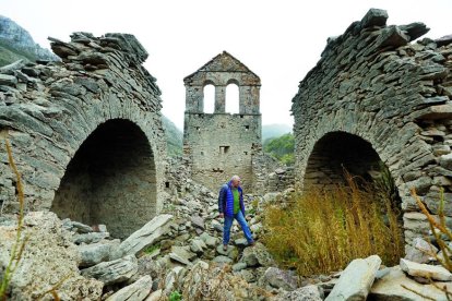 Albito Suárez entre las ruinas de la iglesia de Lagüelles, el pueblo en el que vivió hasta los ocho años y del que los vecinos salieron en barca.