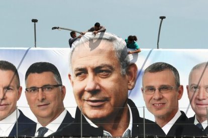 Un grupo de operarios trabaja en una valla publicitaria de propaganda electoral en la que aparece Netanyahu con candidatos de su partido, el Likud, en Jerusalén.