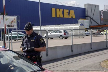 Un agente habla con unos clientes en las afueras del Ikea de Vasteras, en Suecia.