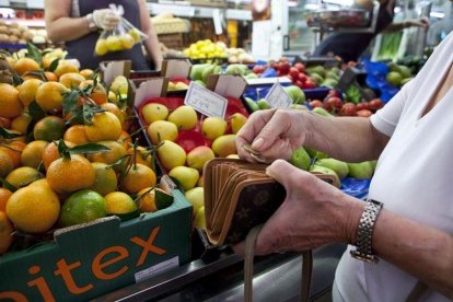 Una mujer llena la cesta de la compra en un mercado de Barcelona.