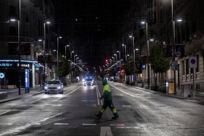 Un operario de los servicios de limpieza cruza la Gran Vía anoche, en la primera jornada de toque de queda en la capital. RODRIGO JIMÉNEZ