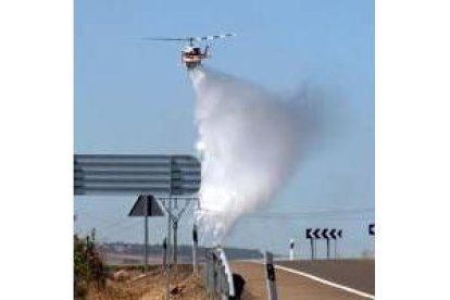 Un helicóptero arroja agua sobre el incendio, cerca de León