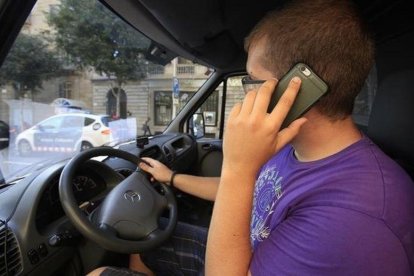 Un conductor habla por el móvil mientras espera el verde del semáforo.