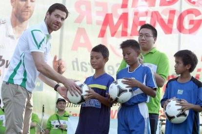 Alonso entrega balones de fútbol a jóvenes locales.