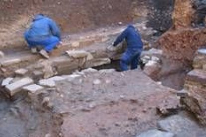 Dos operarios trabajan junto al pavimento de piedra tipo canto de río encontrado en el solar