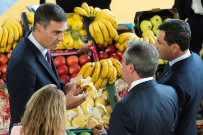 Sánchez (i), el presidente andaluz, Juanma Moreno (d), y el alcalde de Sevilla, Juan Espadas (c), degustan unos plátanos de Canarias durante la inauguración del I Foro Urbano de España y III Foro de Gobiernos locales que se celebra hoy en Sevilla. RAÚL CARO