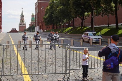 Un padre fotografía a su hijo en una de las últimas vallas que quedaban ayer en Moscú. MAXIM SHIPENKOV