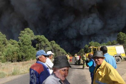 Los vecinos y los miembros de las brigadas y la UME, apesadumbrados ante la columna de humo que se les viene encima.