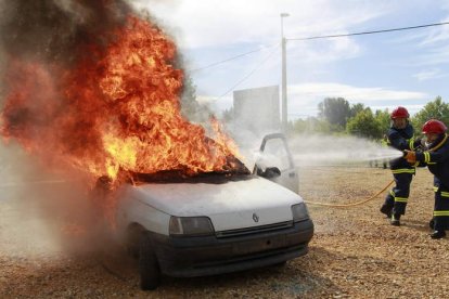 Los bomberos sofocan el fuego tras el simulacro de accidente y rescate de las víctimas.