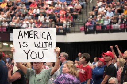 Un seguidor de Trump muestra un cartel con la frase "América te ama" en el mitin del presidente de Iowa.