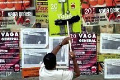 Un ciudadano pega carteles informativos de los diferentes sindicatos sobre la huelga general