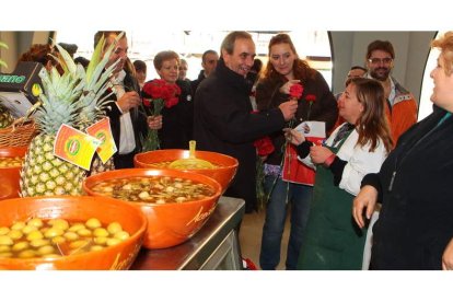 Alonso entrega un clavel a una leonesa en presencia de Nicanor Sen, candidato al Senado, ayer en el mercado del Conde.