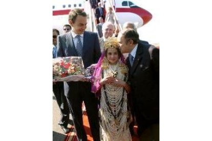 Una niña con el traje argelino recibe a Zapatero con un ramo de flores