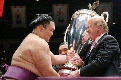 Trump recibe una copa de parte de un luchador de sumo, este domingo en Tokio.