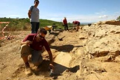 Uno de los excavadores limpia una laja de pizarra que marca una de las tumbas de la necrópolis