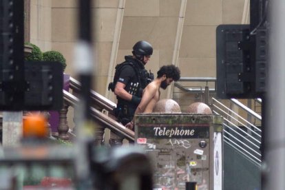 Imagen de un policía británico con uno de los detenidos tras el ataque en el hotel de Glasgow. STRINGER