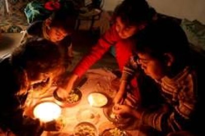 Una familia palestina come a la luz de las velas en la segunda jornada del bloqueo israelí a Gaza