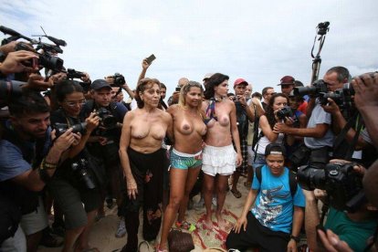 Tres mujeres con los senos desnudos posan para fotógrafos y camarógrafos durante la protesta para exigir la legalización del "topless".