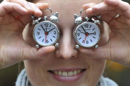 Una mujer muestra dos relojes con el cambio de hora, en una foto de archivo.