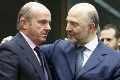 El ministro espanol de Economia, Luis de Guindos, conversa con el comisario europeo de Asuntos Economicos, Pierre Moscovici.