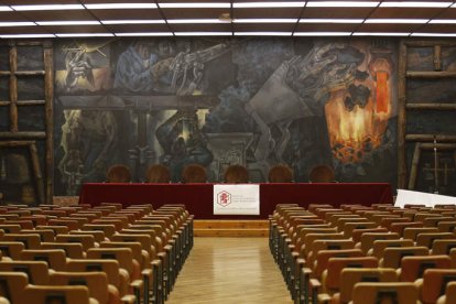 Salón de actos con una de las obras del artista burgalés de fondo.