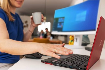 Mujer mira su portátil mientras trabaja desde casa usando el sistema Palm Secure. fujitsu