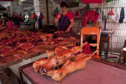 Un carnicero prepara su mostrador con carne de perro lista para ser cocinada en el festival de Yulin.