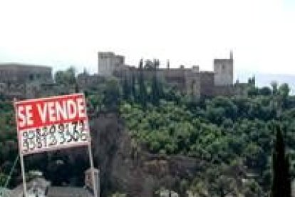 Un cartel anunciando la venta de una propiedad se recorta sobre la Alhambra de Granada