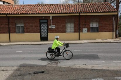 Una mujer sube en bicicleta por la carretera que comunica Armunia con la Valdoncina