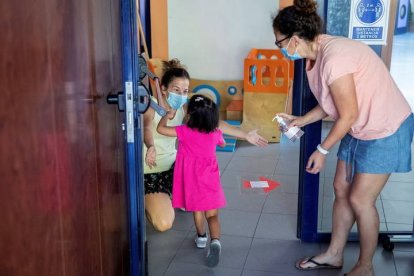 Una educadora saluda a una niña durante la reapertura de la escuela infantil. RODRIGO JIMÉNEZ