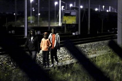 Tres inmigrantes se encaminan por las vías del tren con la intención de acceder al Eurotúnel, cerca de Calais.