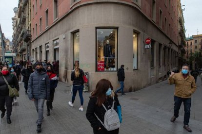 Varios transeúntes pasan ante un comercio del centro de Barcelona, ayer. ENRIC FONTCUBERTA