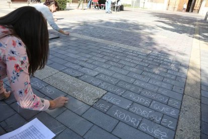 Dos jóvenes escriben en tiza en la plaza de San Marcos los nombres de los presos y represaliados de la Guerra Civil