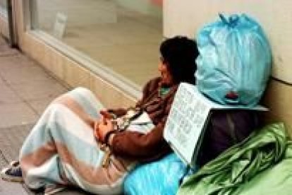 Un mendigo descansa en una calle al lado de sus pertenencias, en una fotografía de archivo