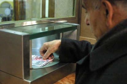 Un hombre ingresa dinero en la ventanilla de una entidad bancaria.