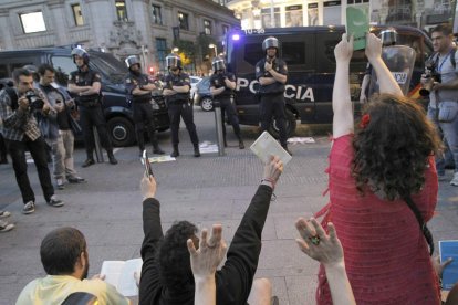 Un grupo de estudiantes protesta alzando libros con las manos ante la policía impasible.