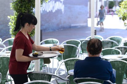 Una camarera sirve una consumición esta mañana en una terraza. NACHO GALLEGO