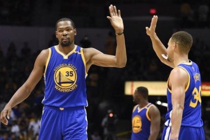 Kevin Durant choca con Stephen Curry durante un partido de pretemporada contra los Lakers.