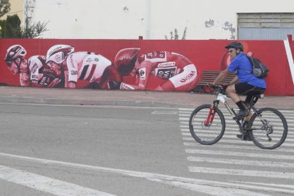 Un ciclista pasa por delante del mural alusivo a la Vuelta a España 2023 situado en la calle Julio Hernández de La Bañeza. RAMIRO