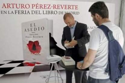 El escritor Arturo Pérez-Reverte firma libros al primer lector de la larguísima cola.