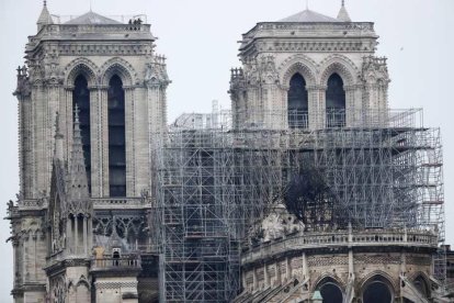 Varios bomberos trabajan en lo alto de una de las torres de la catedral de Nôtre Dame.